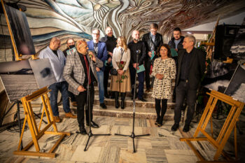 Zdjęcie. Autorzy fotografii z wystawy Krajobraz Niepokorny stoją na schodach pod płaskorzeźbą Adama Wolskiego przedstawiającą czarodziejskie drzewo. Wśród nich - dyrektor KCK Augustyna Nowacka.