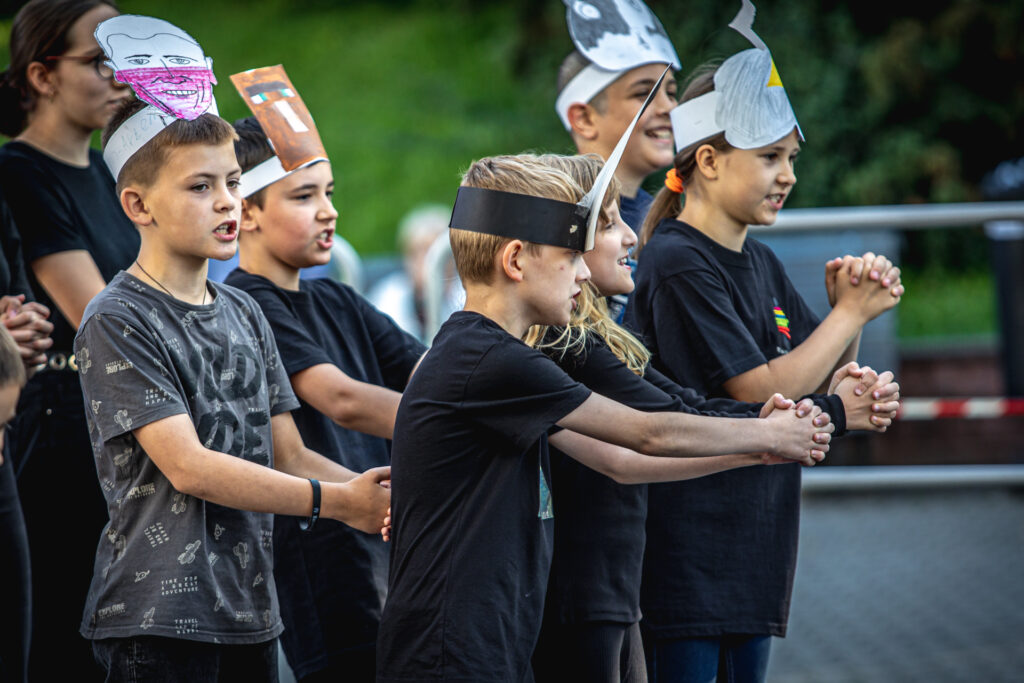 Zdjęcie. Grupa dzieci trzyma przed sobą ręce z zaplecionymi palcami.