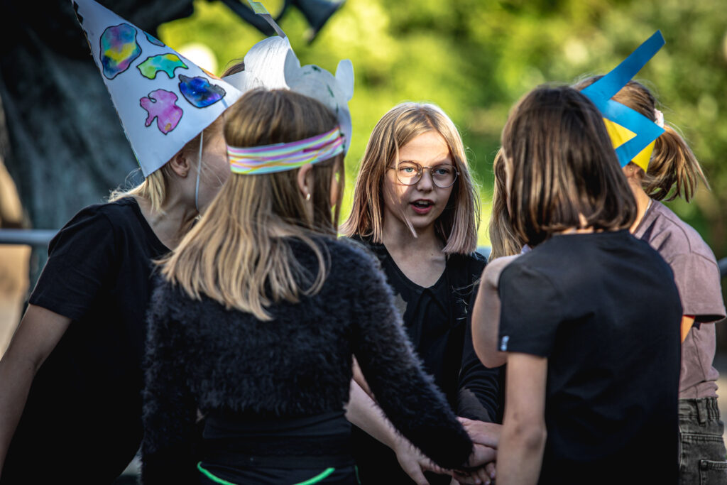 Zdjęcie. Grupa dziewczynek stoi przodem do siebie w kółku.