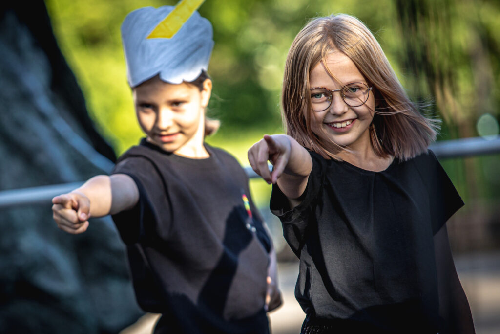 Zdjęcie. Dwie uczestniczki zajęć mają prawe ręce wyciągnięte do przodu. Pokazują coś palcem wskazującym. Obie się uśmiechają.