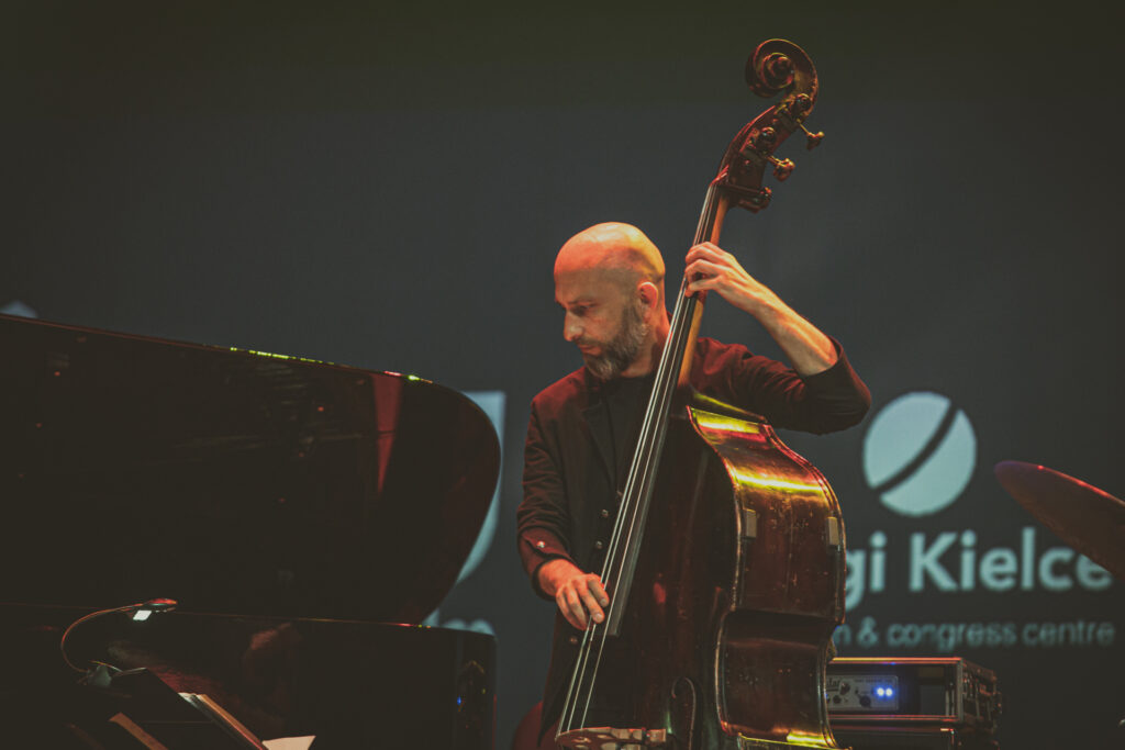 Zdjęcie. Kontrabasista gra palcami na instrumencie.