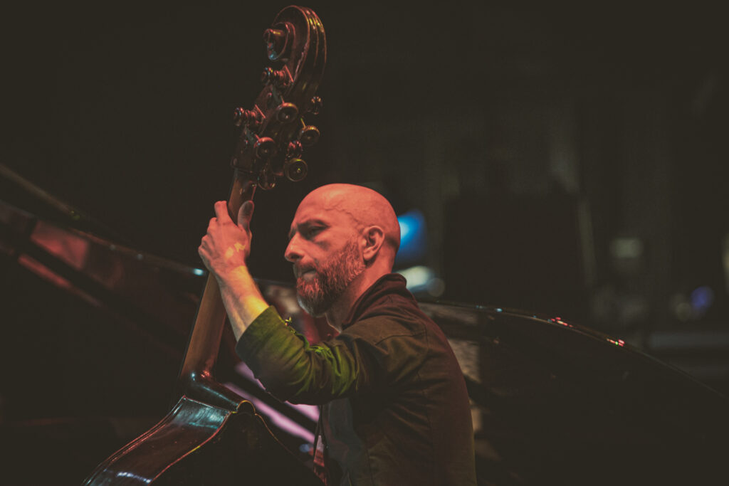 Zdjęcie. Łysy kontrabasista gra na instrumencie.
