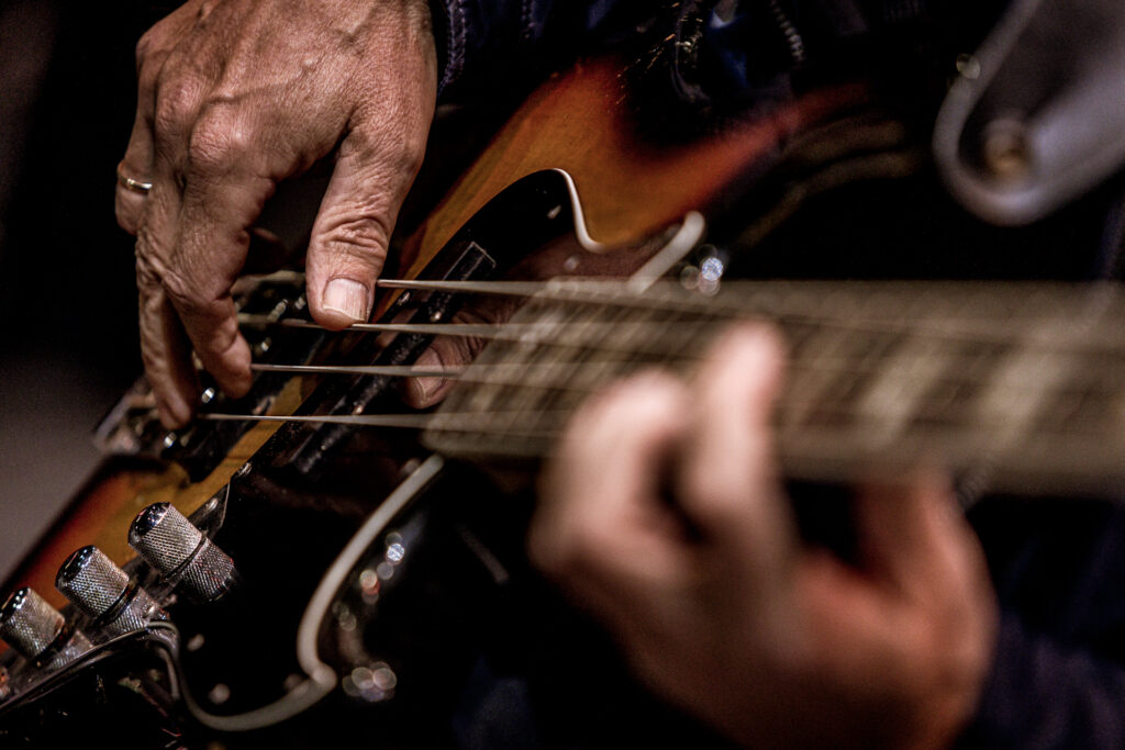 Zdjęcie. Zbliżenie dloni grających na gitarze,