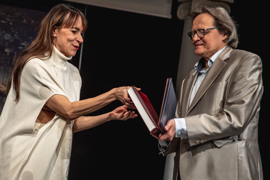 Zdjęcie. Tancerka Małgorzata Ziółkowska wręcza grubą książkę Andrzejowi Skorupskiemu.