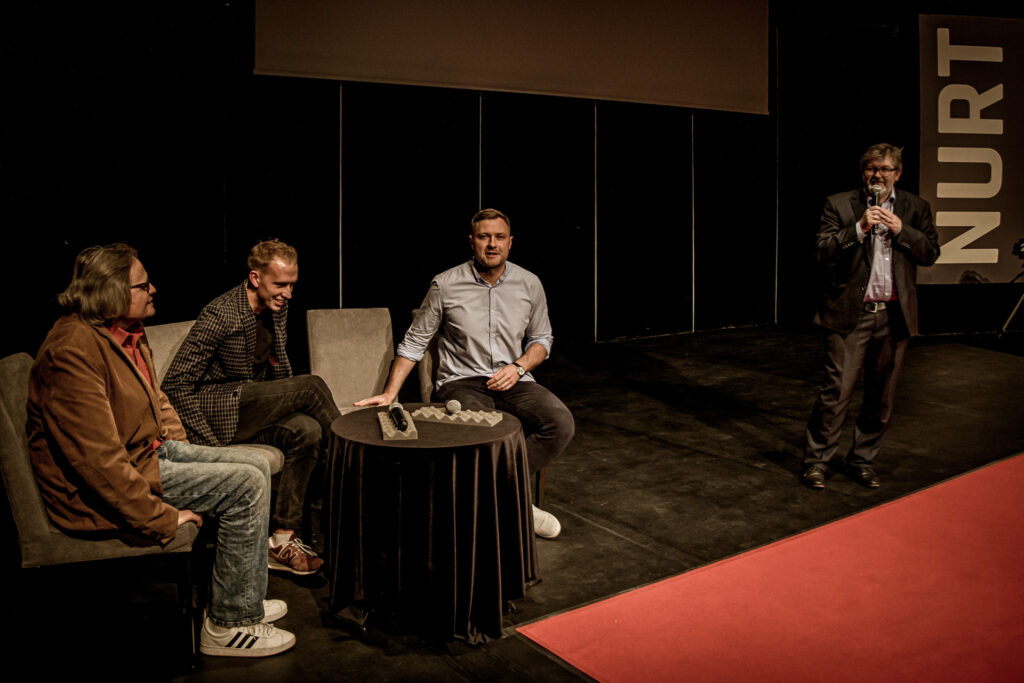 Zdjęcie. Mała SCena KCK. Przy okrąglym stoliku siedzą: Andrzej Skorupski, Marian Wąchała i Krzysztof Zięba. Obok stoi kierownik impresariatu Robert Wieczorek.