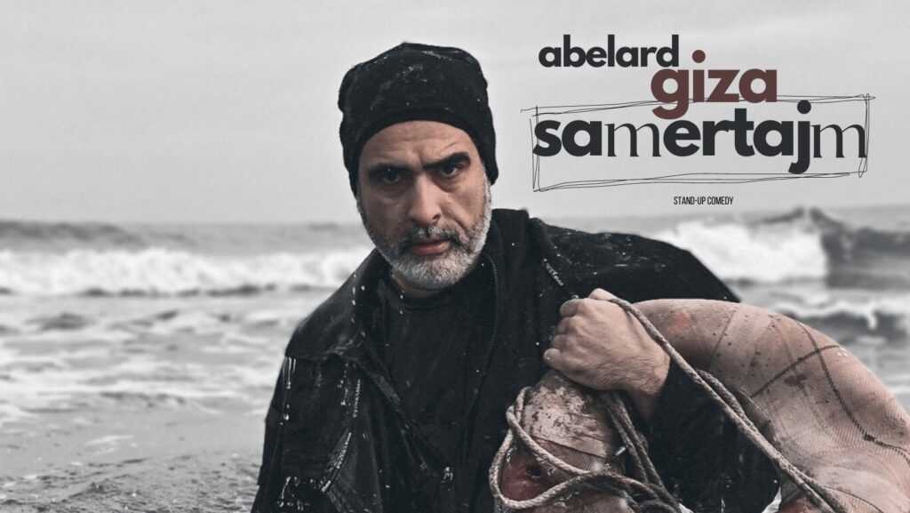 Grafika. Zdjęcie mżęczyzny z siwą brodą w czarnej czapce na tle morza. Po proawej stronie napis: Abelard Giza. Samertajm. Stand-up comedy.