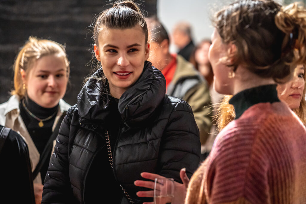 Zdjęcie. Publiczność wernisażu wystawy "Autoportret". Za pierwszym planie 3 młode kobiety.