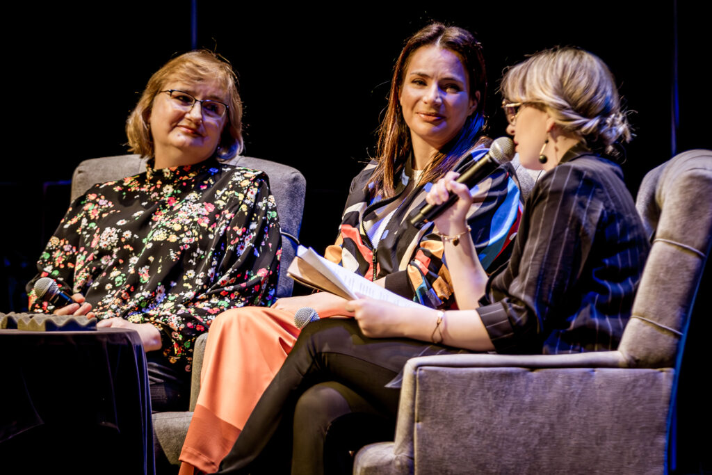 Zdjęcie.Spotkanie z Anną Dereszowską. Przy stoliku siedzą trzy panie. Od lewej: Małgorzata Klimas z fundacji SOS Wioski Dziecięce, aktorka Anna Dereszowska i prowadząca spotkanie Aleksandra Niemczyk.