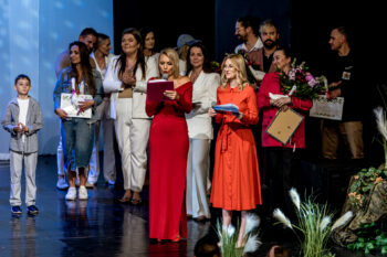Zdjęcie. Prowadzące koncert dla Malinki. Za nimi przedstawiciele instytucji, które wsparły koncert. M.in. wicedyrektor KCK Artur Wijata.