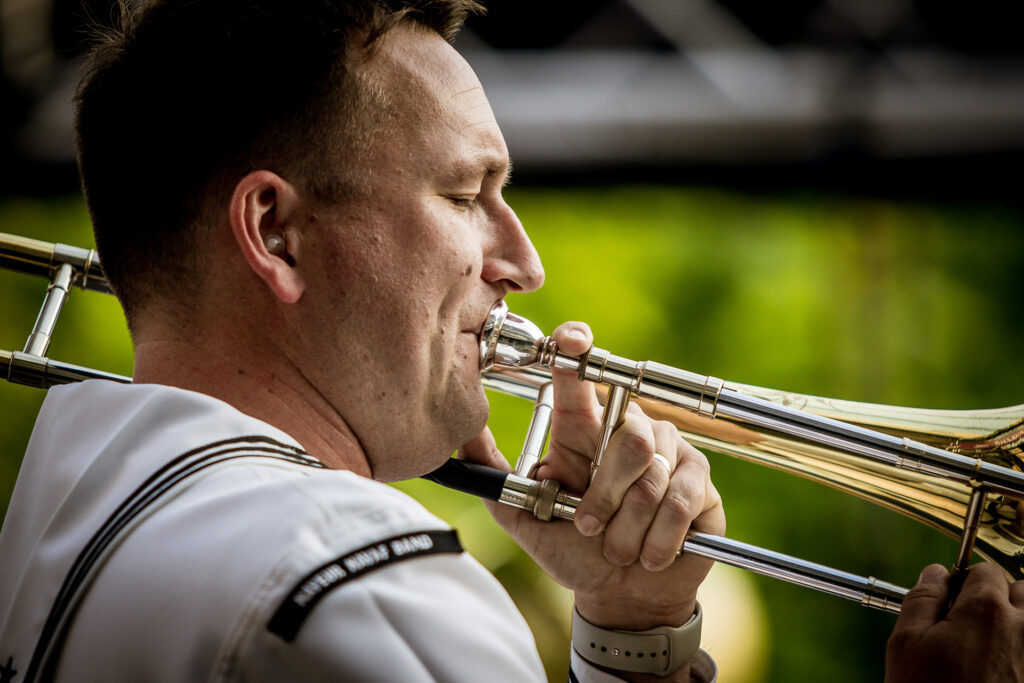 Zdjęcie. Mężczyzna gra na puzonie. To muzyk z zespołu Topside Band.