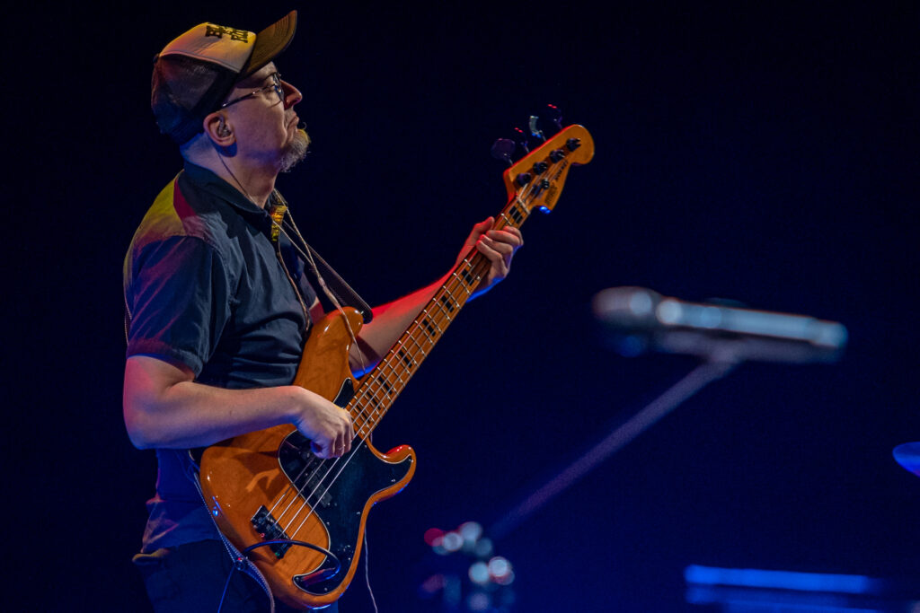 Zdjęcie. Muzyk w czapce besjbolówce gra na gitarze elektrycznej.