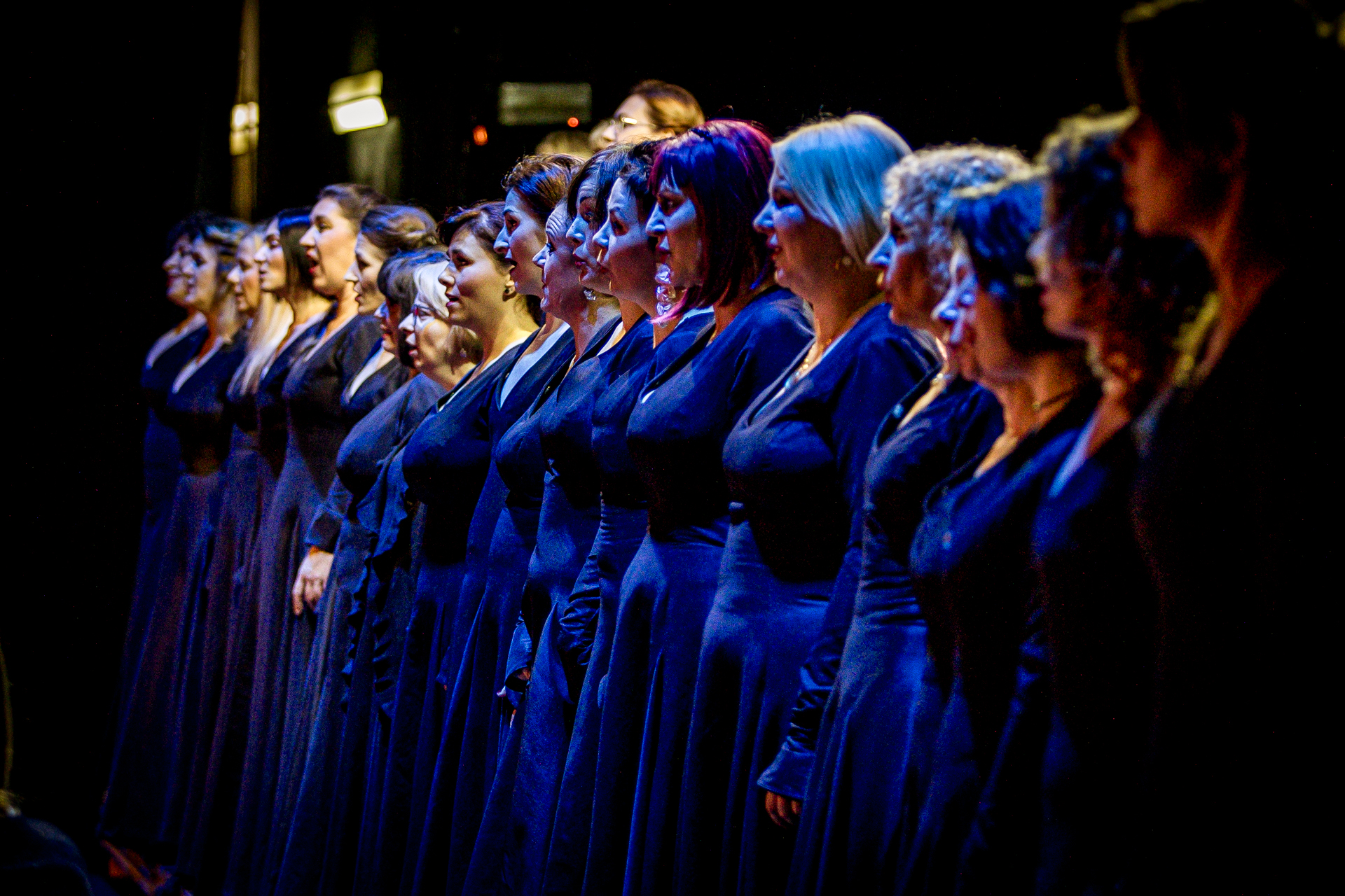 Zdjęcie. Chórzystki w ciemnych niebieskich długich sukniach stoją w jednym rzędzie. To chór opery "Straszny Dwór".
