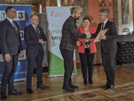 Zdjęcie. Wicedryektor KCK Artur Wijata odbiera wyróżnienie z rąk senatora Krzysztofa Słonia.