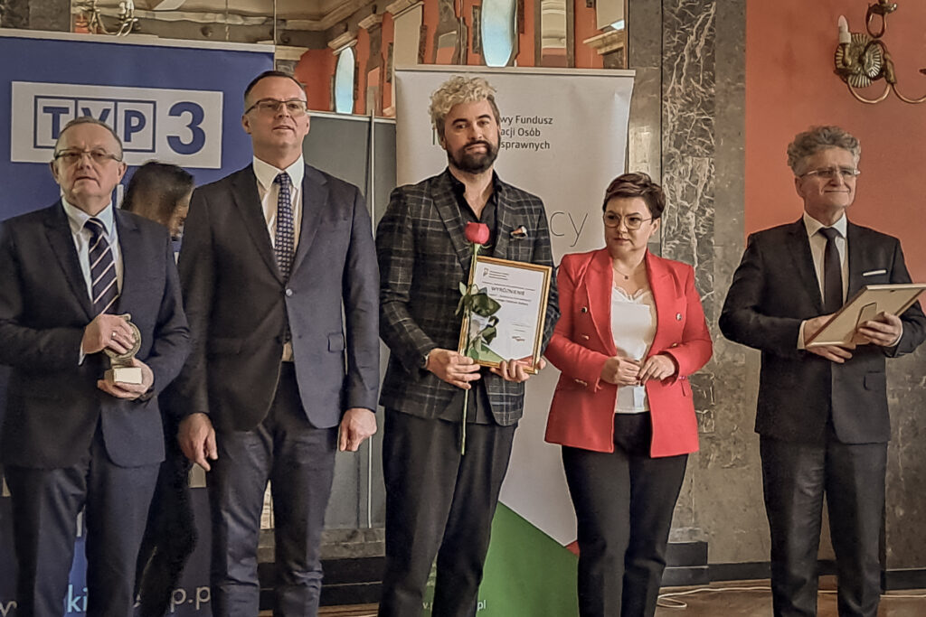 Zdjęcie. Artur Wijata pozuje w rzędzie z wręczającymi nagrody.