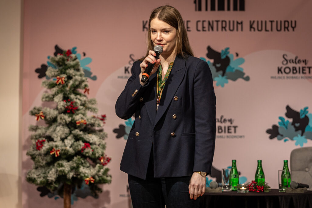 Zdjęcie. Ciemna blondynka o długich prostcyh włosach mówi do mikrofonu. To dyrektor KCK Agata Klimczak-Kołakowska.