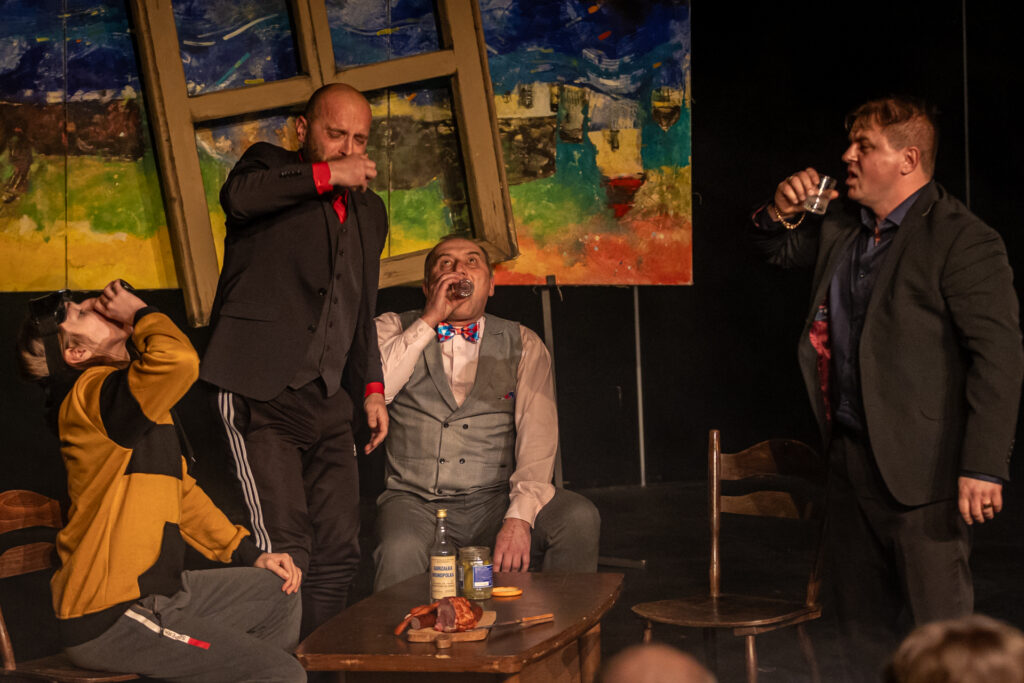 Zdjęcie. Czterech mężczyzn przechyla szklanki z wódką. To aktorzy Teatru Ciut Frapującego. Spektakl "Narty Ojca Świętego".