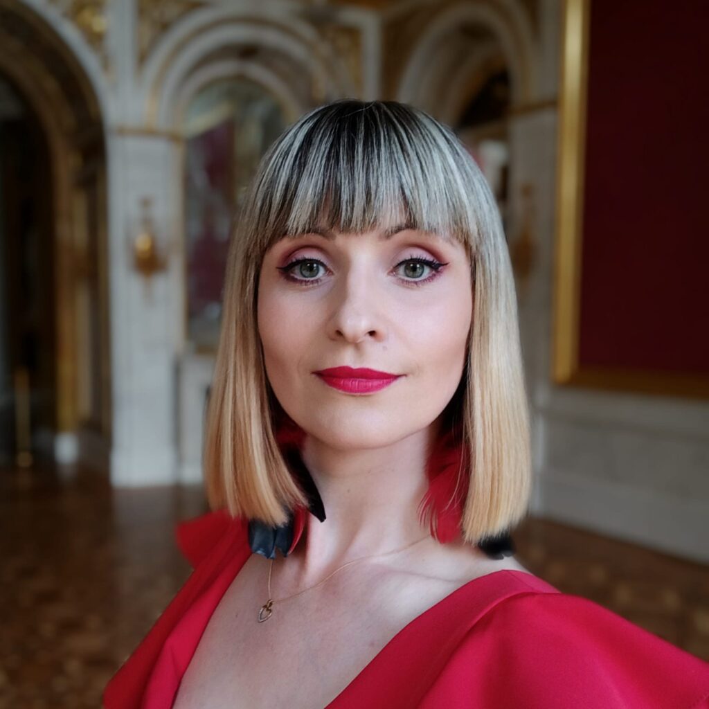 Zdjęcie. Blondynka o prostych włosach do ramion z grzywką do brwi. To Natalia Skipor, mezzosproanistka.