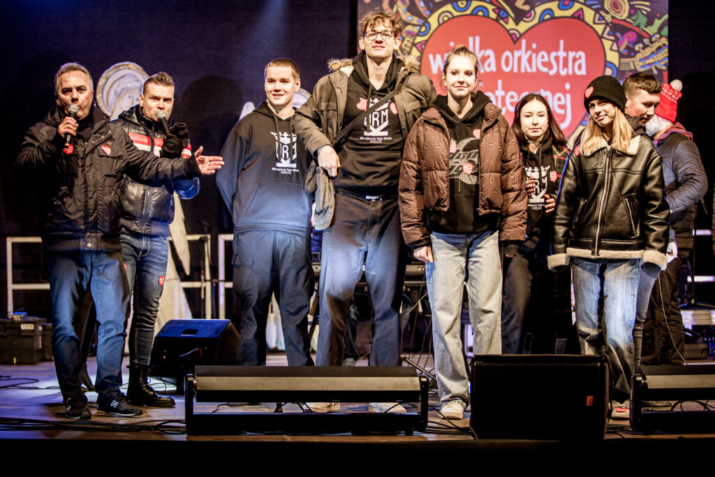 Zdjęcie. Duża grupa młodzieży i dwóch prowadzących na scenie WOŚP KCK.