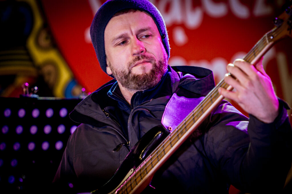 Zdjęcie. Gitarzysta z brodą gra na gitarze.