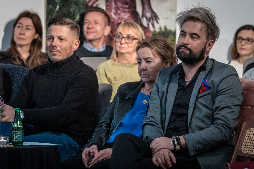 Zdjęcie. Na krzesłach siedzą widzowie salonu z Ewą Ewart. W pierwszym rzędzie mężczyzna w czarnym golfie, szczupła kobieta w niebieskeij bluzce i męćzyzna z jasną grzywką i ciemną brodą. To Marcin Chłodnicki, wiceprezydent Kielc, Marzena Sobala i wicedyrektor KCK Artur Wijata.