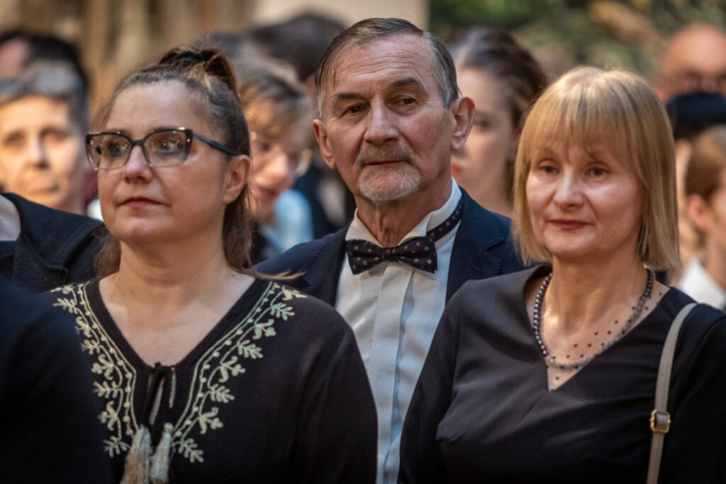 Zdjęcie. Trzy osoby w średnim wieku: siwiejącym mężvzyzna, dwie panie: brunetka z długimi wlosami spiętymi w kucyk na czubku głowy i blondynka z grzywką na czole i prostymi włosami do ramion patrzą przed siebie.