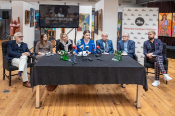 Zdjęcie. Stół przykryty czarnym suknem w galerii Winda. Za stołem siedzą trzy panie i czterech panów. Przed nimi mikrofony stacji telewizyjnych i radiowych. Kobieta po środku, z długimi włosami i prostym przedziałkiem mówi do mikrofonu. To dyrektor KCK Agata Klimczak-Kołakowska.