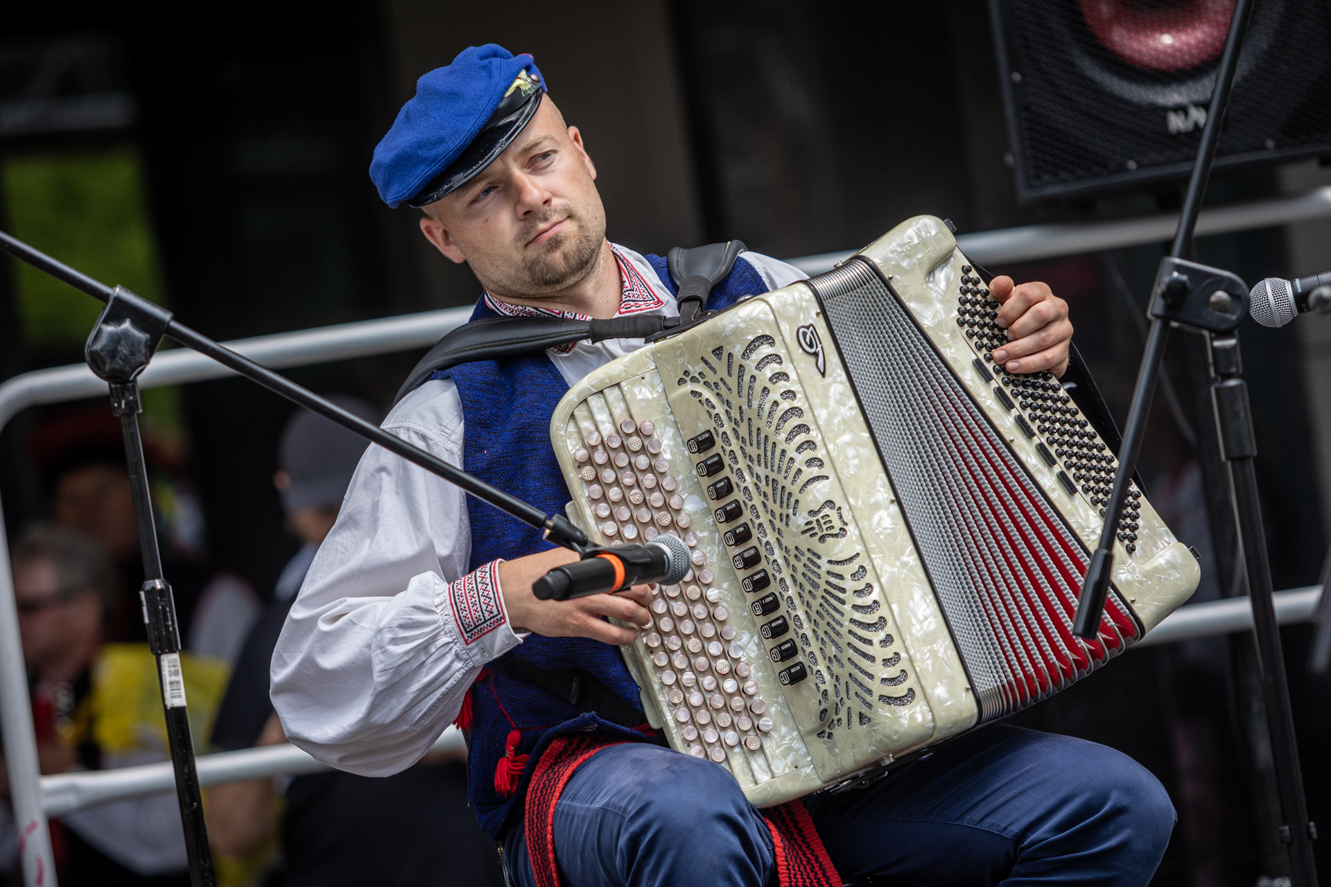 Zdjęcie. Młody mężczyzna w niebieskiej czapce z daszkiem gra na jasnej harmonii.