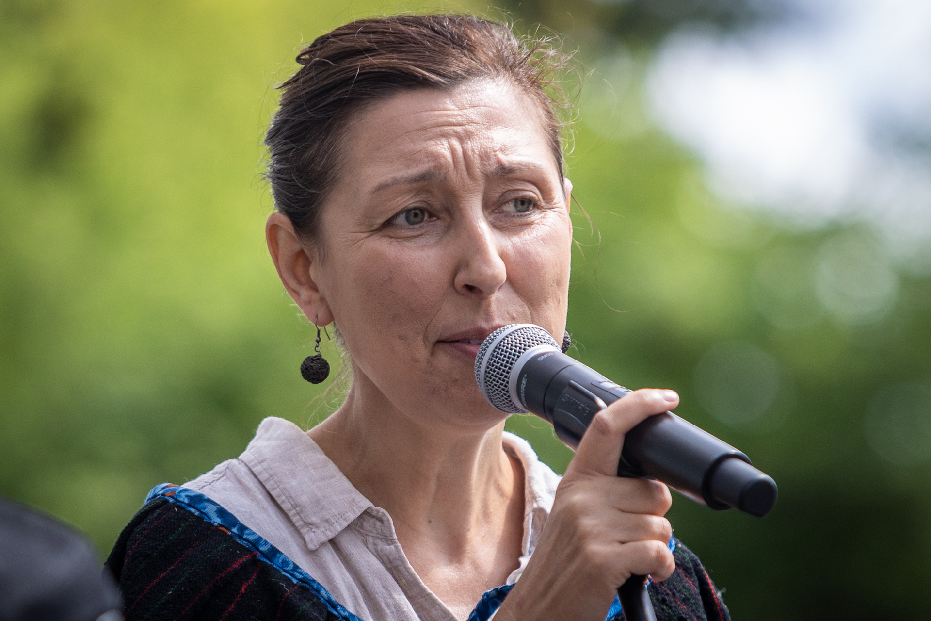Zdjęcie. Szczupła brunetka śpiewa do mikrofonu.