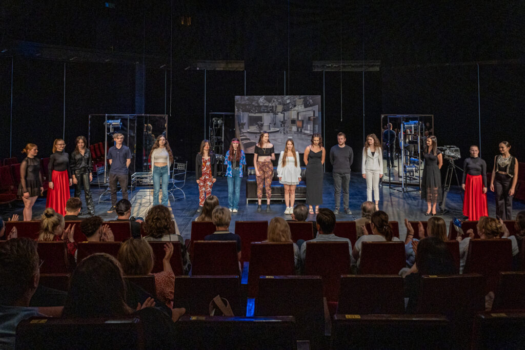 Zdjęcie. Grupa młodych ludzi - dziewczyny i chłopaki stoją na scenie w jednym rzędzie. To aktorzy teatru Pegaz.