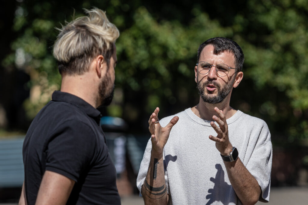 Zdjęcie. Meżczyzna z brodą tłumaczy coś mężczyźnie z jasną grzywką. To Rafał Lis i wicedyrektor KCK Artur Wijata.