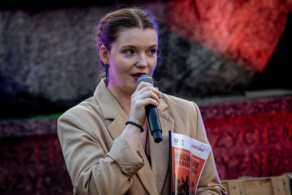 Zdjęcie. Kobieta w beżowej marynarce mówi do mikrofonu. To dyrektor KCK Agata Klimczak-Kołakowska.