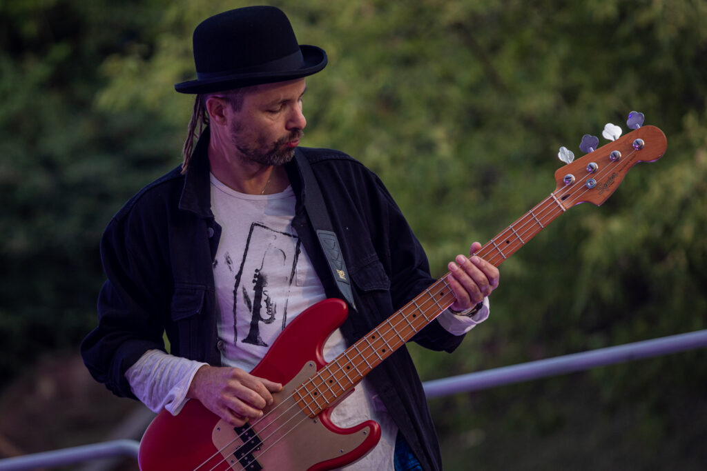 Zdjęcie. Mężczyzna w czarnym meloniku gra na gitarze elektrycznej.