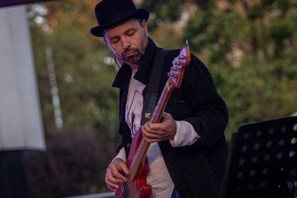 Zdjęcie. Mężczyzna w meloniku gra na gitarze elektrycznej.