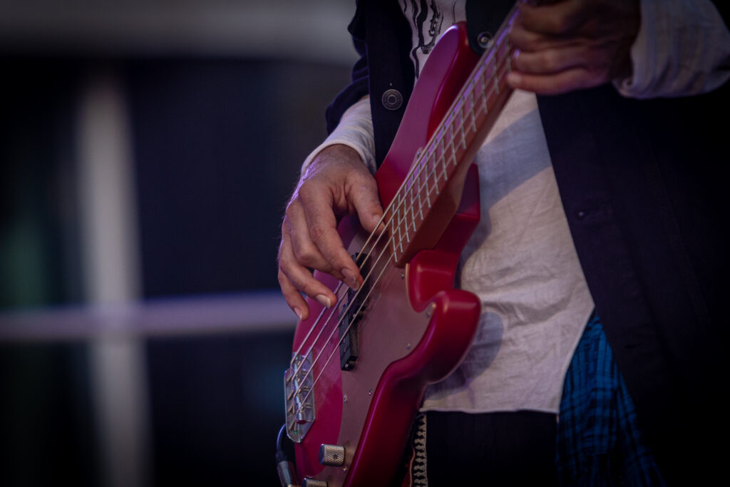 Zdjęcie. Czerwona gitara elektryczna. Męskie dłonie na instrumencie.