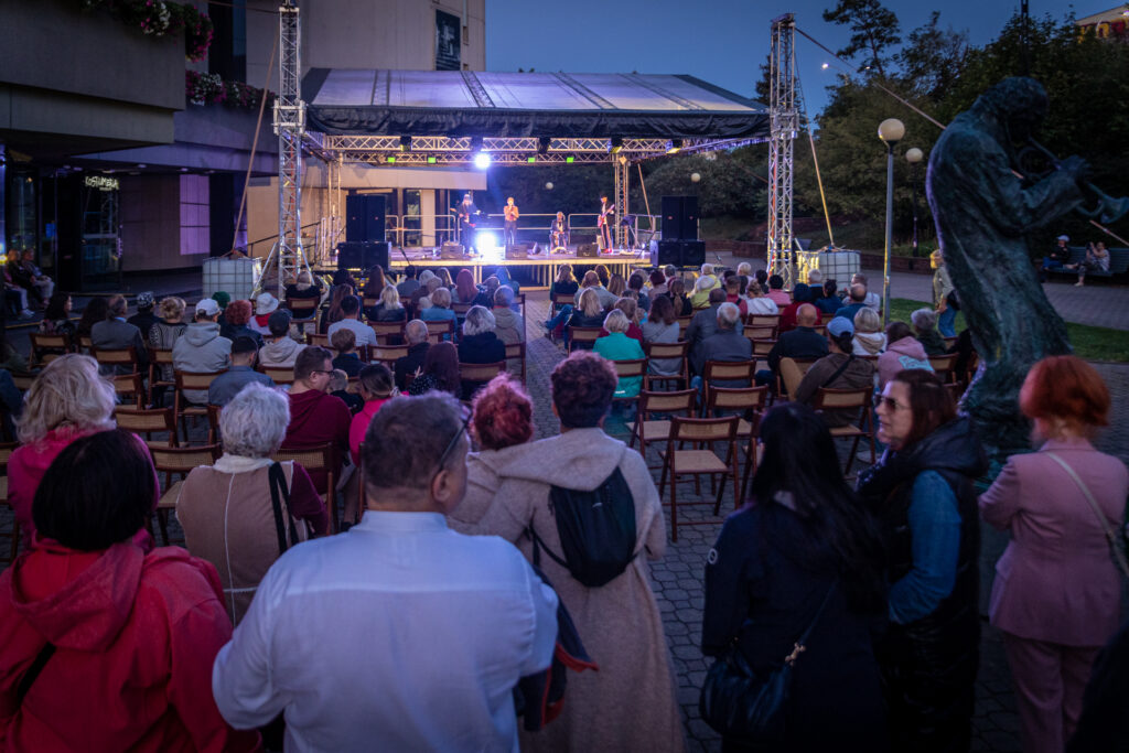 Zdjęcie. Letnia SCena KCK podczas koncertu DobroBand. Duża grupa ludzi patrzy w kierunku sceny.