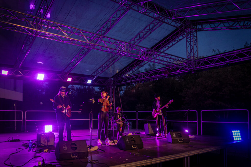 Zdjęcie. Zespól DobroBand na scenie Letniej. Zapada zmrok, muzyków oświetlają fioletowe reflektory.