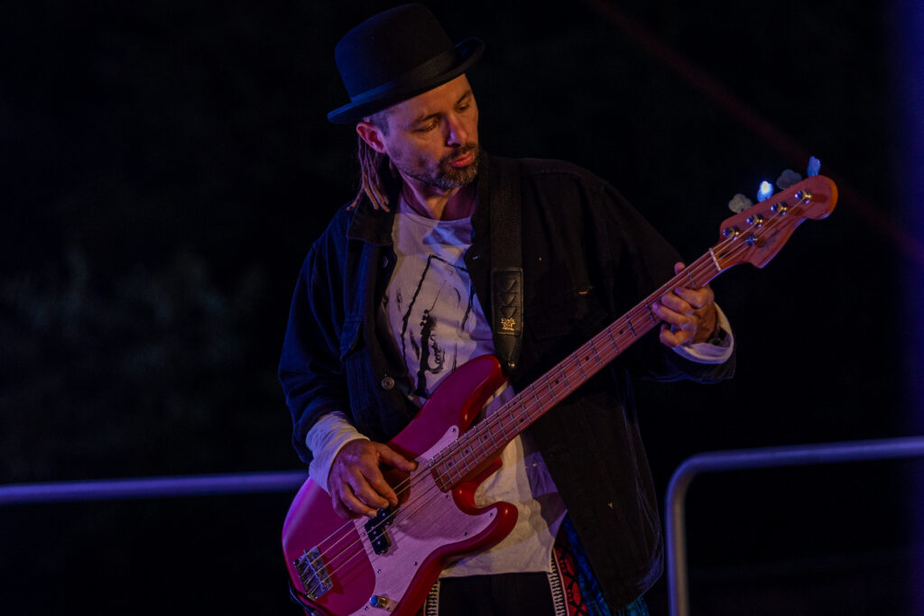 Zdjęcie. Mężczyzna w czarnym meloniku gra na gitarze elektrycznej.