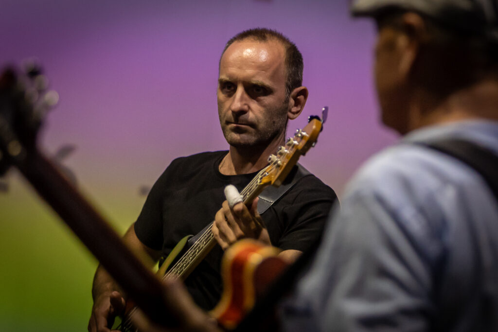 Zdjęcie. Łysiejący mężczyzna gra na gitarze.