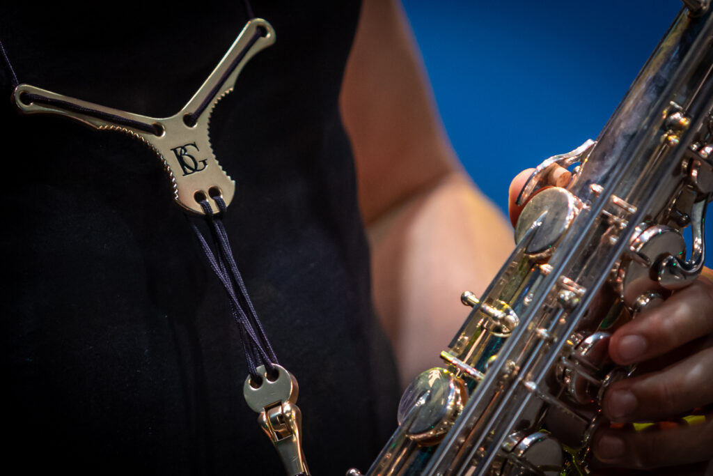 Zdjęcie. Smycz trzymająca metalowy instrument dęty na szyi muzyka.