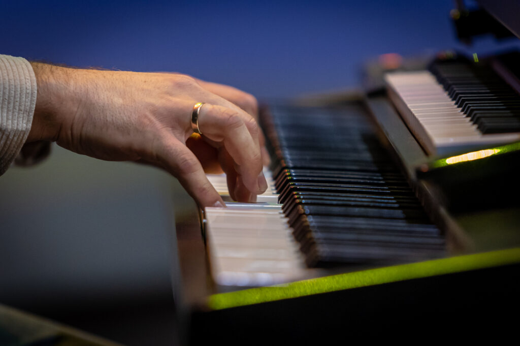 Zdjęcie. Męskie dłonie z obrączką na placu grające na instrumencie klawiszowym.