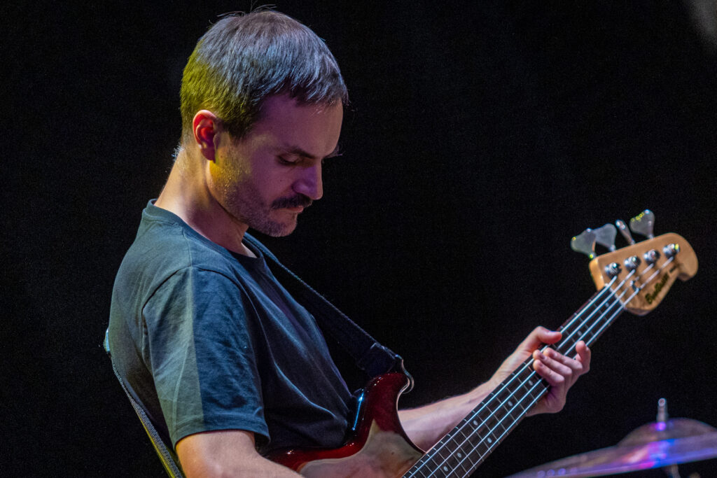 Zdjęcie. Ciemnowłosy mężczyzna z wąsami gra na gitarze.