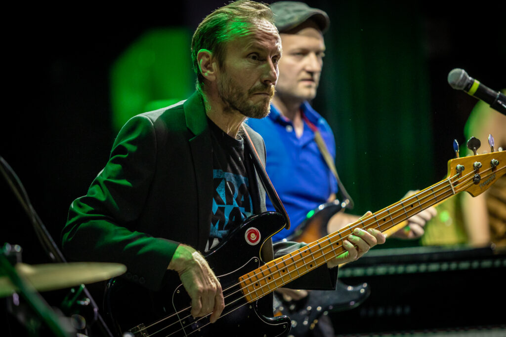 Zdjęcie Szczupły mężczyzna z wąsami i brodą gra na gitarze.