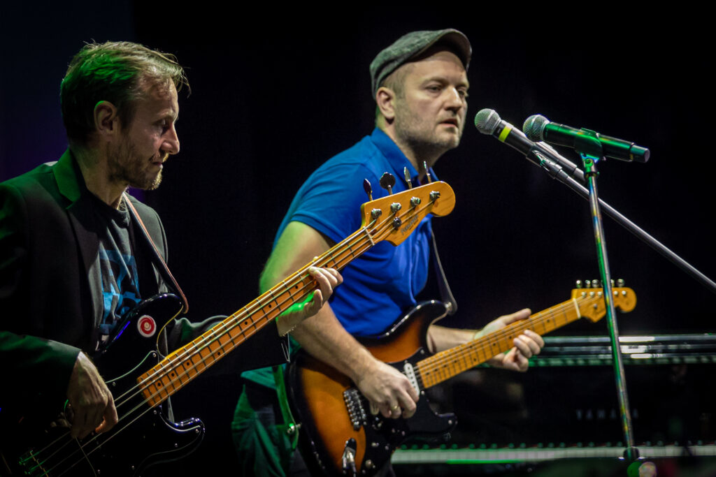 Zdjęcie. Dwóch muzyków z gitarami na scenie.
