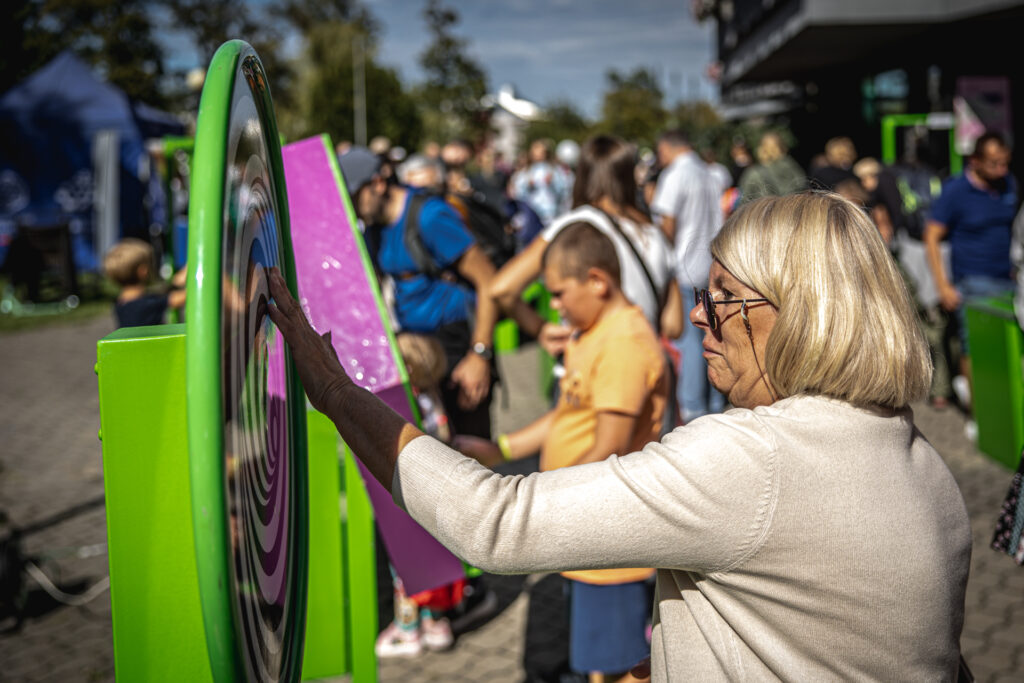 Zdjęcie. Kobieta dotyka ręką tarczy z pomalowanymi biało-czarnymi spiralami.