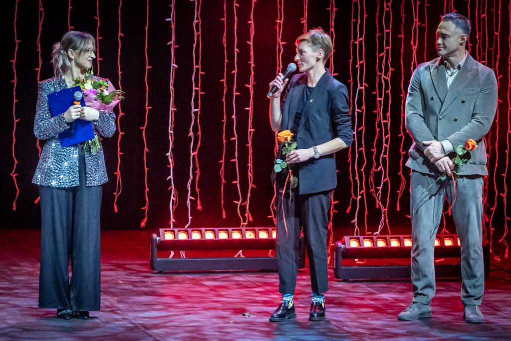 Zdjęcie. Prezydentka Agata Wojda mówi do mikrofonu. Kobieta patrzy w kierunku prowadzącej koncert Aleksandry Młynarczyk. Z drugiej strony prezydentki stoi radny i prezes fundacji Perspektywy Maciej Burstein.