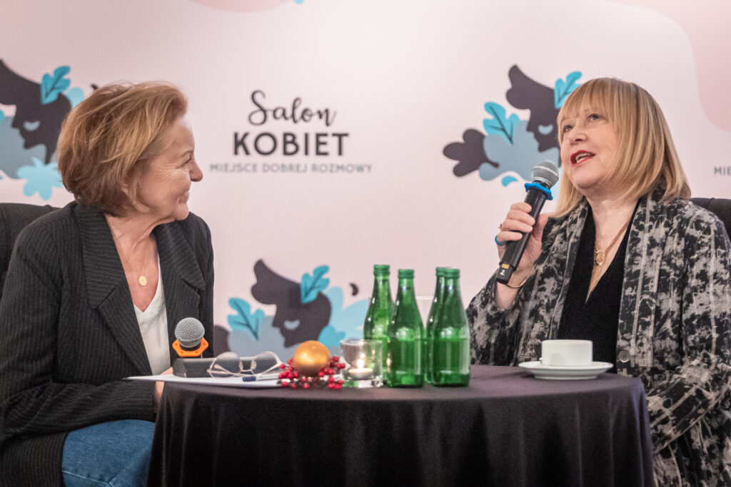 Zdjęcie. Dwie kobiety siedzą przy stoliku i rozmawiają. To Marzena Sobala - dziennikarka i Joanna Żółkowska aktorka.