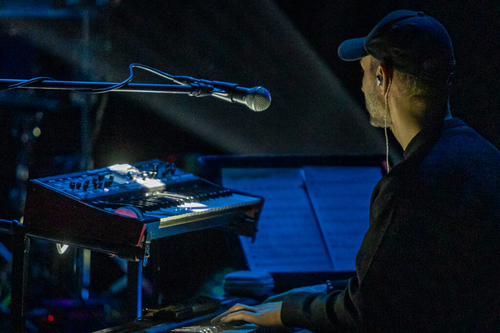 Zdjęcie. Mężczyzna w czapce z daszkiem gra na keyboardzie.