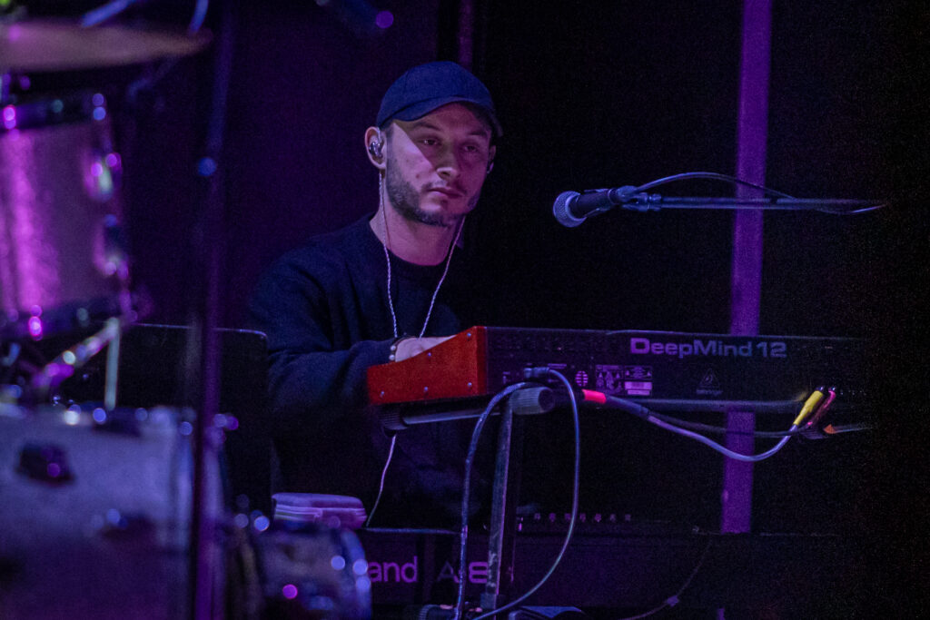 Zdjęcie. Mężczyzna w czapce z daszkiem gra na keyboardzie.