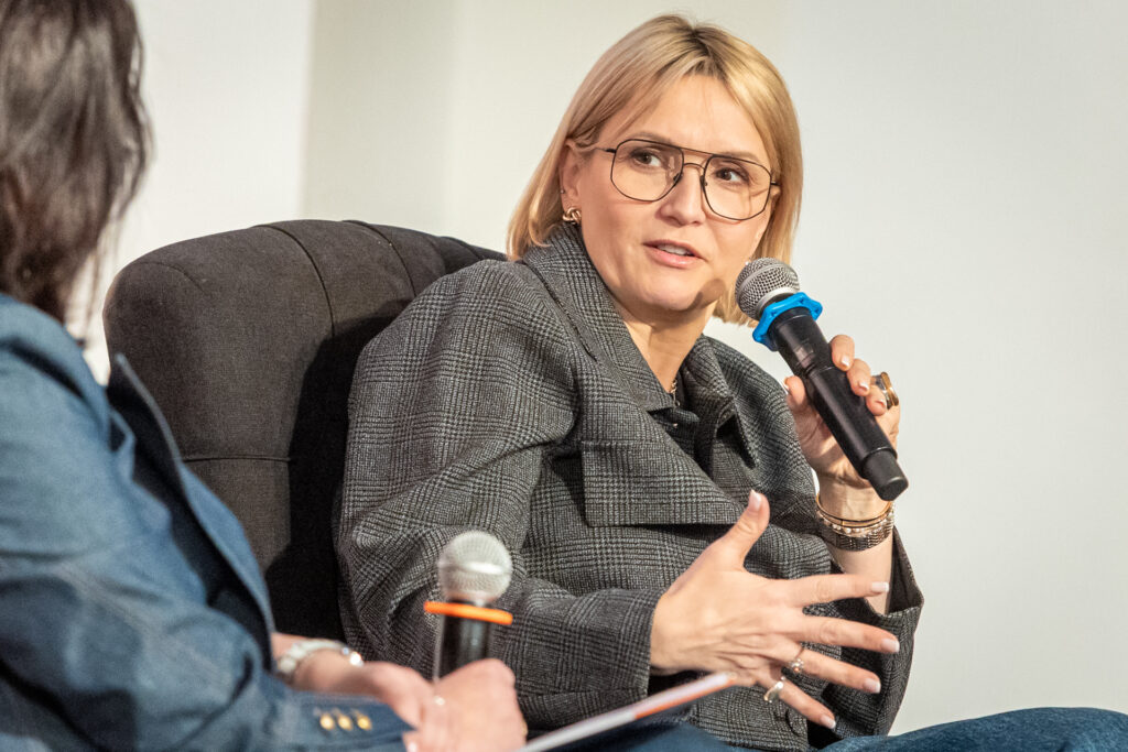 Zdjęcie. Blondynka - Marta Kuligowska dziennikarka TVN24 mówi do mikrofonu.