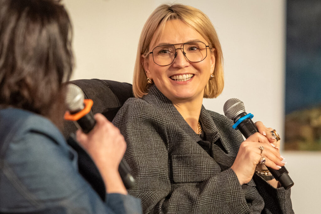 Zdjędynka w okularach patrzy w kierunku brunetki. To Marta Kuligowska podczas Salonu Kobiet. ncie. Uśmiechnięta blo